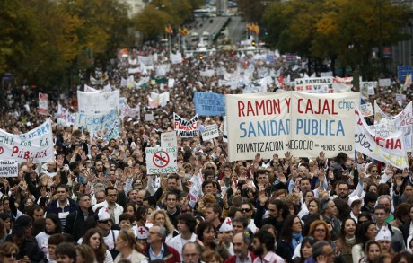 Demonstrators raise their hands as they take part in a protest against local government's plans to cut spending on public health care in Madrid
