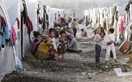 Kurdish refugees from the Syrian town of Kobani sit in front of their tents in a camp in the southeastern town of Suruc